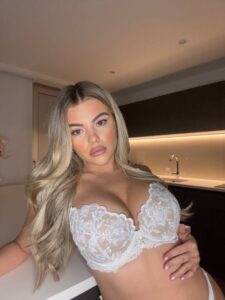 British OnlyFans Model in white lingerie poses confidently in a modern kitchen, showcasing her style and personality.